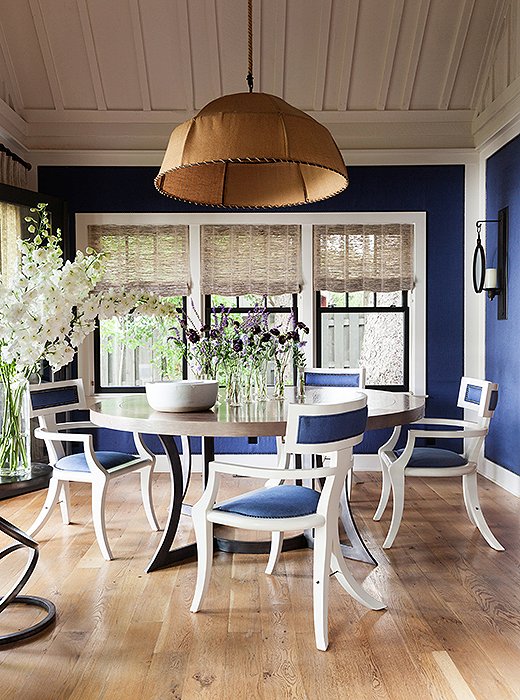 The walls of the dining room and the dining chairs are upholstered in the same rich blue and finished with the same nail-head trim. The muffling qualities of the fabric keeps dinner parties from getting too loud.
