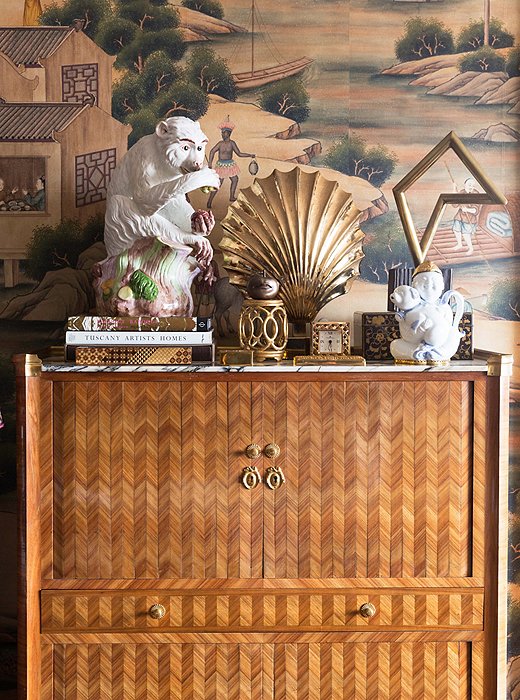 An inlaid-wood secretary, found in a New Orleans auction, shows off a curated vignette in radiant, golden hues. The hand-painted wallpaper is a custom creation by Gracie.
