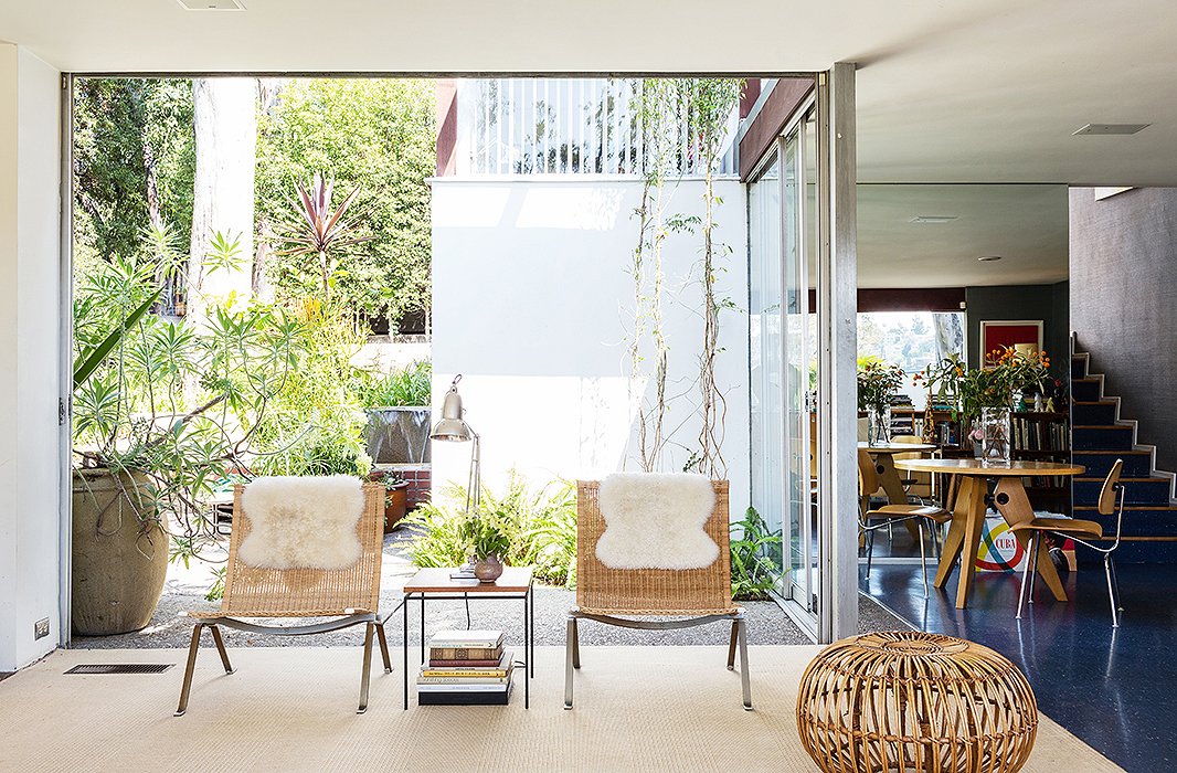 Natural elements (and nature) help ease up the sleek lines of the glass-encased home, playing up the great California promise of living outdoors. The PK22 chairs, by Poul Kjaerholm from Wyeth, and a neutral carpet keep open the view into the interior courtyard.
