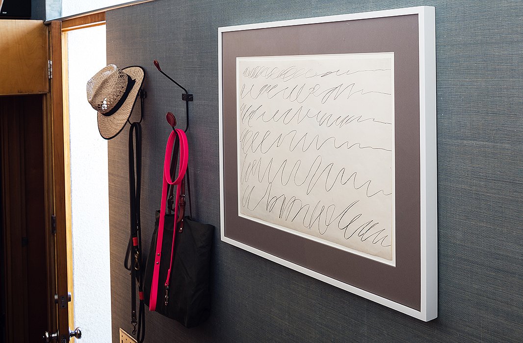 A Cy Twombly drawing hangs near the entry against blue grasscloth wallpaper, which is used throughout the house “just to get out of the recurring syndrome of white and brown,” says David.
