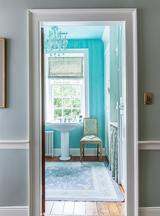 In the bathroom, the Venetian glass chandelier in a bright turquoise-aqua color was inspired by the original 1920s bathtub, which had been aqua.
