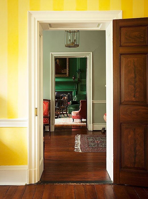 The view from the sunshine-yellow sitting room into the deep emerald-green library.
