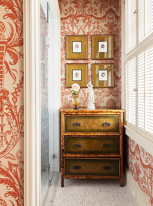 A powder room was redone with a swirling red-and-white wallpaper.
