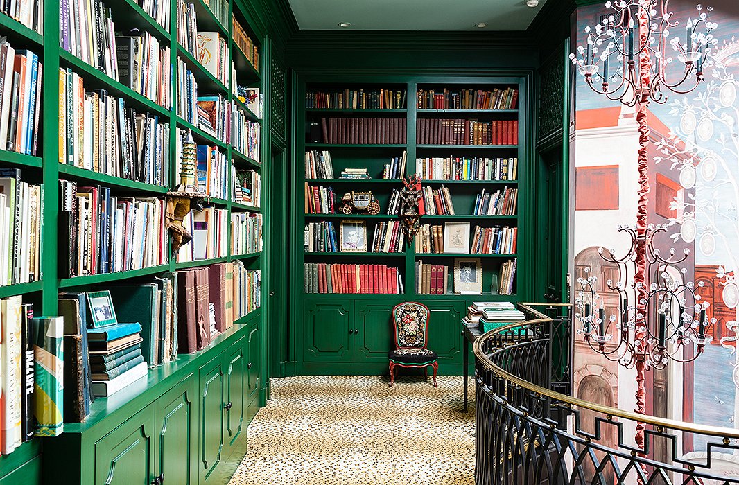 Lacquered in emerald green, the built-in wall-to-wall bookcases are home to eclectic objects, such as scale models and seashells, as well as a colorful array of favorite books.

