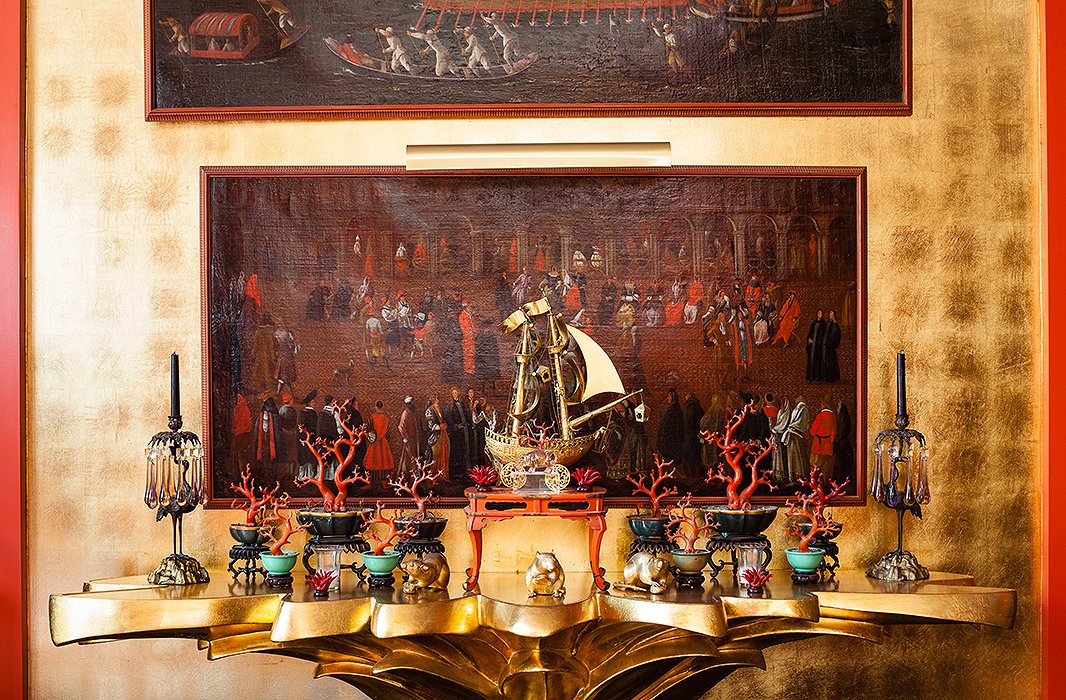 Seventeenth-century Venetian paintings hang above a console created by costume designer Don Loper in the 1940s. The 18th-century Chinese lacquer coral branches are from the collection of Elsie de Wolfe.
