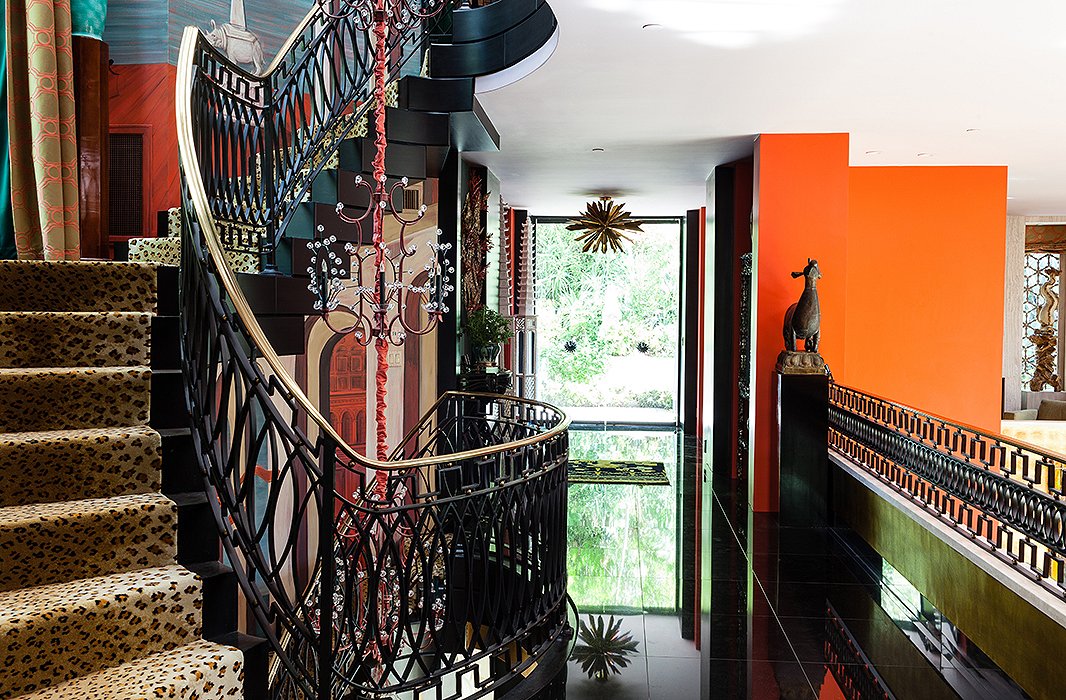 The street-level entrance opens up to a black-granite stairway, hall, and mezzanine that overlooks the drawing room one floor below. The sunburst light fixture in the entry is by Tony Duquette for Remains Lighting.
