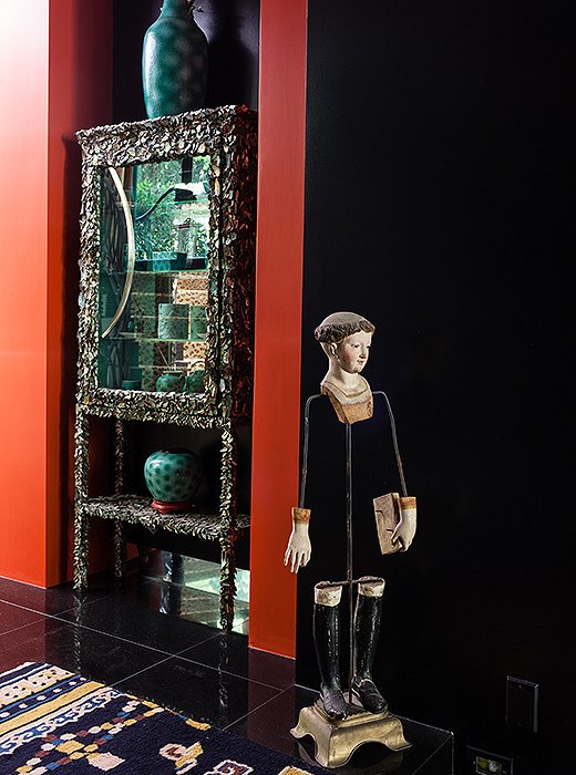 In a passage near the entry, an 18th-century statue of an Italian saint stands guard by an abalone shell, a coral branch, and a pearl display case made by Duquette.
