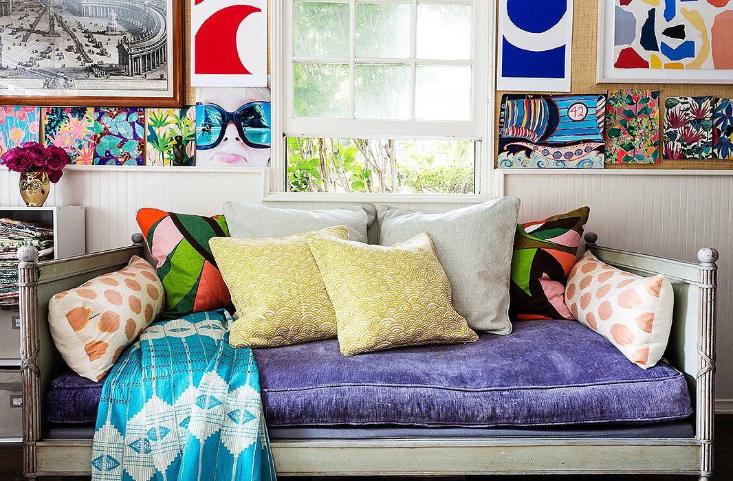 The designer hangs her new work, alongside work that’s inspiring her, over the daybed in the studio. One picture is an overlay she did atop a photo of one of her sons wearing sunglasses.
