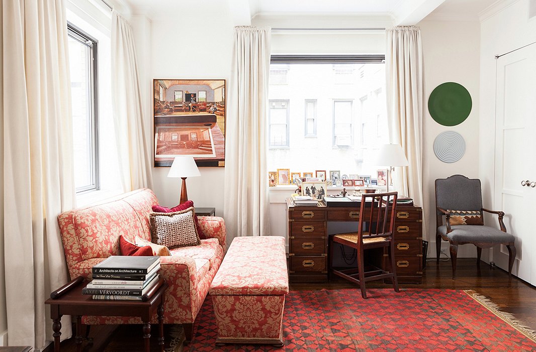 In her otherwise pale apartment, Mariette’s home office, featuring an antique couch and ottoman covered in original fabric and a striking black-and-red rug, testifies to her love of color and pattern. It’s also her favorite place to relax and watch the news. The painting is by George Deem and the oil-on-plywood discs are by Rupert Deese.
