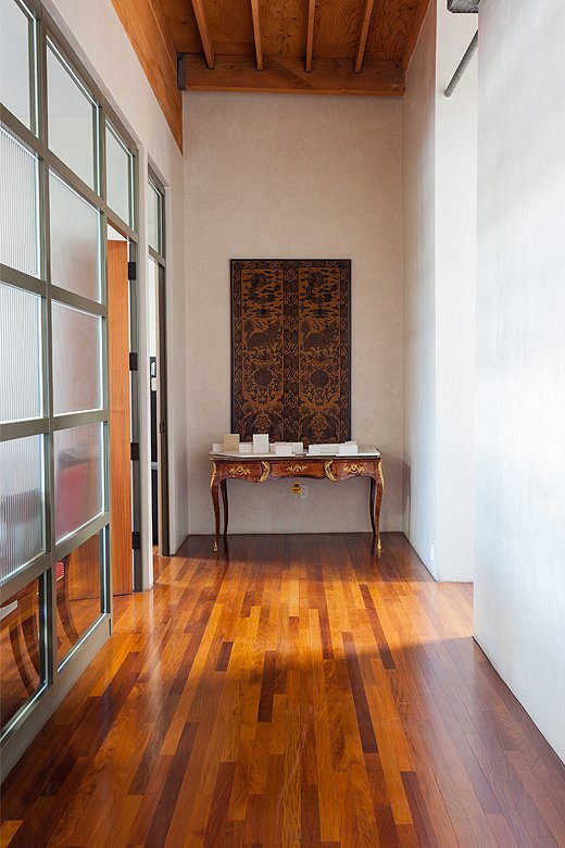 In the hallway leading to the main conference room, a 19th-century Chinese panel hangs above an antique desk.
