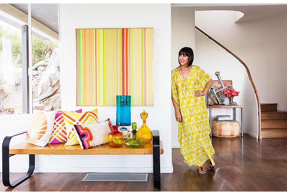 A vintage bench is topped with an array of Trina’s own pillows, colored glass vessels, and an estate-sale score. “This striped painting is not done by anyone noteworthy but feels high-end,” she says.
