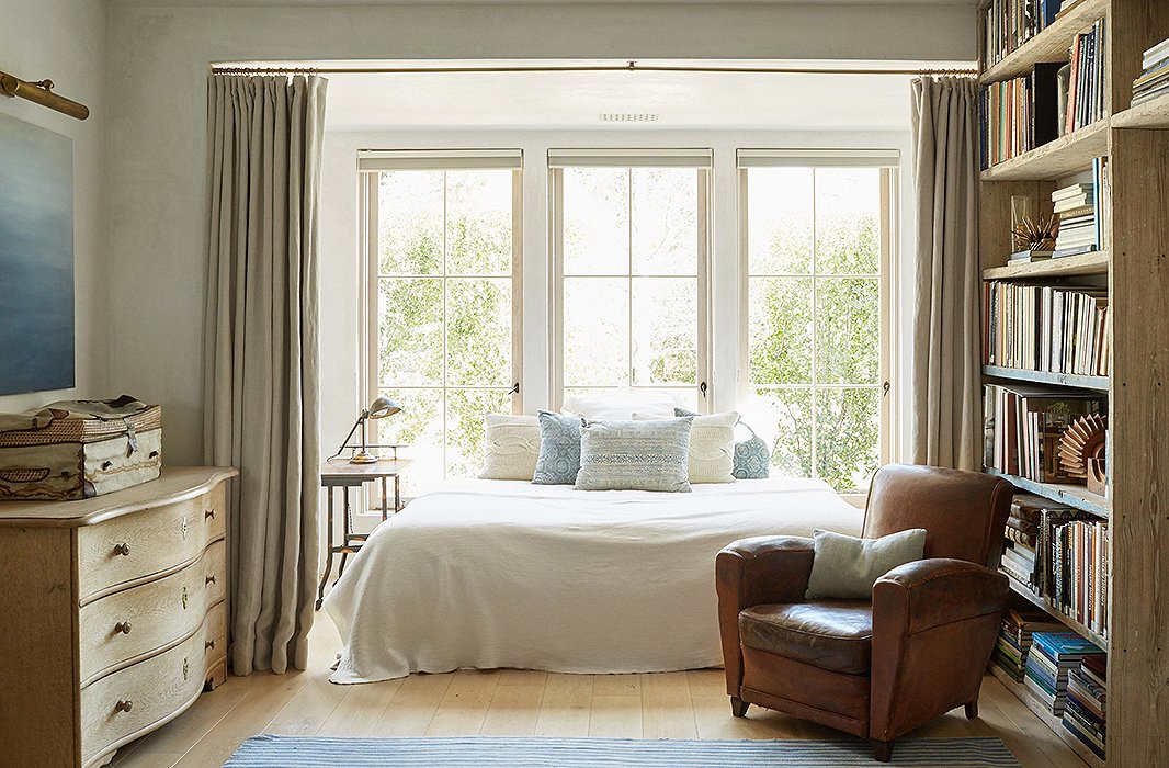 The bed has a new life as a reading nook. The linens are from Libeco, and the pillows are vintage from Giannetti Home. The comfy leather armchair was found at an antiques show.
