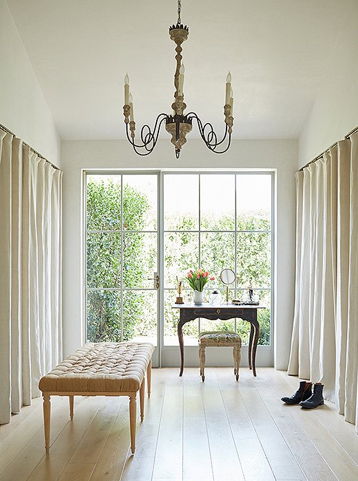 The dressing room feels like a still life. “We begin and end our day here, so we kept it calm and uncluttered,” says Brooke. “And we left a lot of room on the floor to stretch and play with the pups.” The linen panels conceal hanging clothes.
