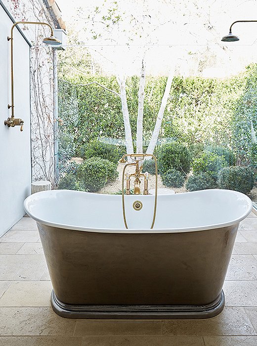 To create a “greenhouse atmosphere” in the master bath, floor-to-ceiling sheets of glass envelop the pewter tub and shower and connect the space to the garden—filled with boxwoods, blue hydrangeas, and campanulas—just outside.
