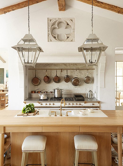Above the Lacanche range, copper and stainless-steel cookware is within easy reach. The stone quatrefoil is from Belgium. Limestone was used for the range’s backsplash.
