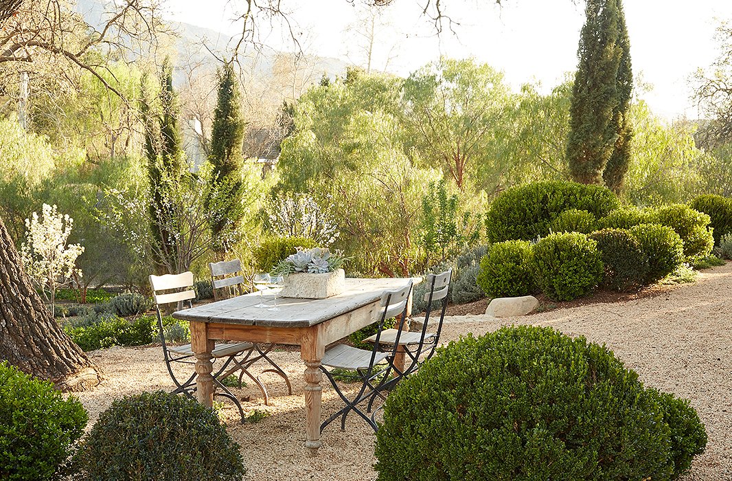 “We’re very casual. We just pass plates of grilled chicken or fish and salads through the kitchen windows and eat family-style here,” says Brooke. The table is from a shuttered antiques shop, and the chairs are vintage. Hanley gold gravel defines the area.
