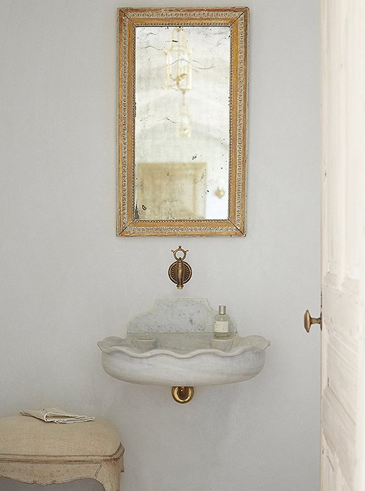 The powder room reflects the couple’s signature mix of rustic and refined. A marble sink found in Belgium is suspended on the wall, and a fountain spout finds new life as a faucet. The mirror is from Marston Luce Antiques in Washington, DC.
