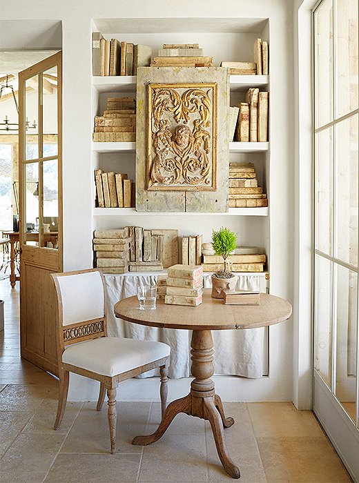 The exposed plaster shelves in Brooke’s office display her collection of antique paper and vellum books. Brooke meets with her design associates at the table, while just beside it a natural linen curtain hides dog and rabbit supplies.
