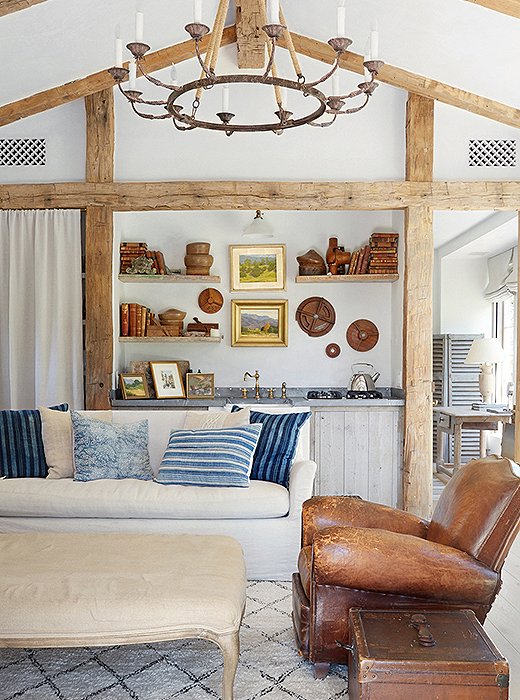 The guesthouse feels like an “artist’s studio”—a bucolic design filled with collections of classical pieces including vintage landscape paintings and ornamental plaster. Antique barn beams frame the kitchen area.
