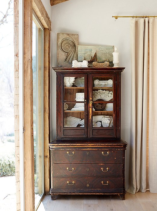 An antique Italian cabinet with embossed leather interior adds storage and is a display place for ornamental plaster pieces. “Like in Steve’s office, we used large single-pane glass to provide great views of the pond and the donkeys,” says Brooke.
