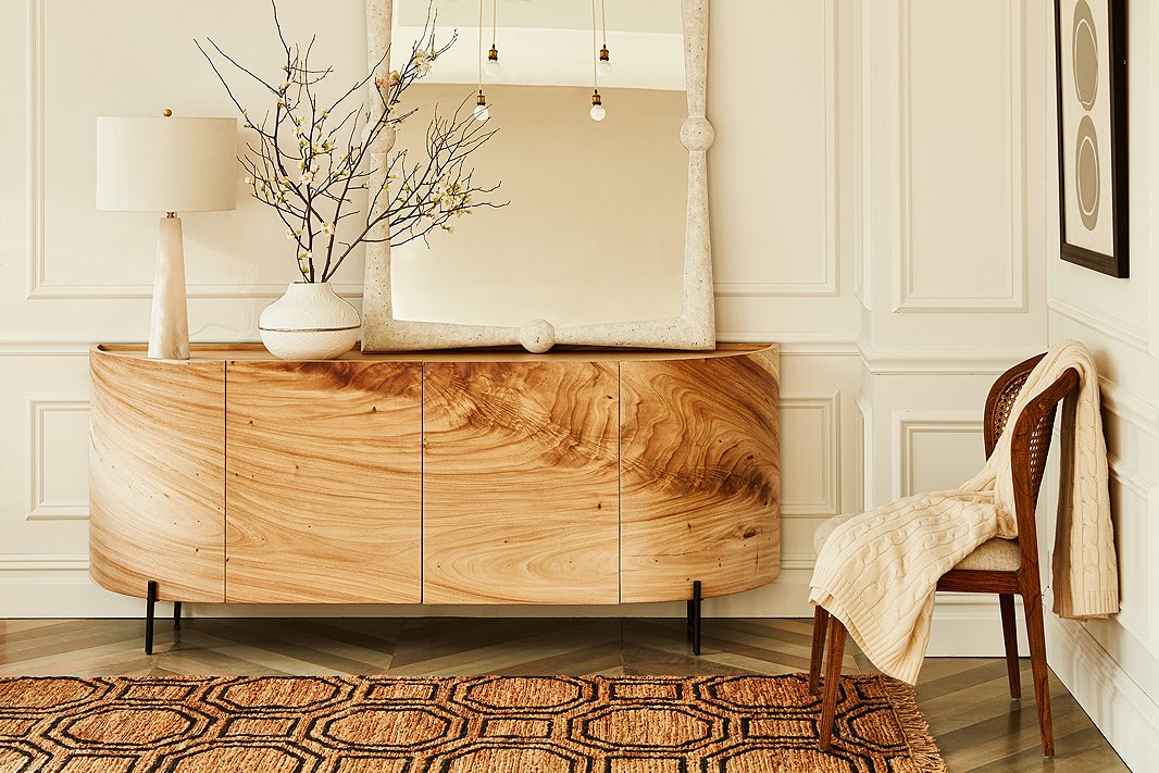 Shown above: the Bryn sideboard, which has shelves behind its doors; the Scarlett resin wall mirror; and the Hexile jute rug.
