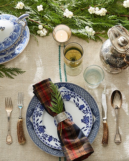 Mismatched blue-and-white plates, silver details, and an evergreen garland feel fresh on this autumnal holiday.  
